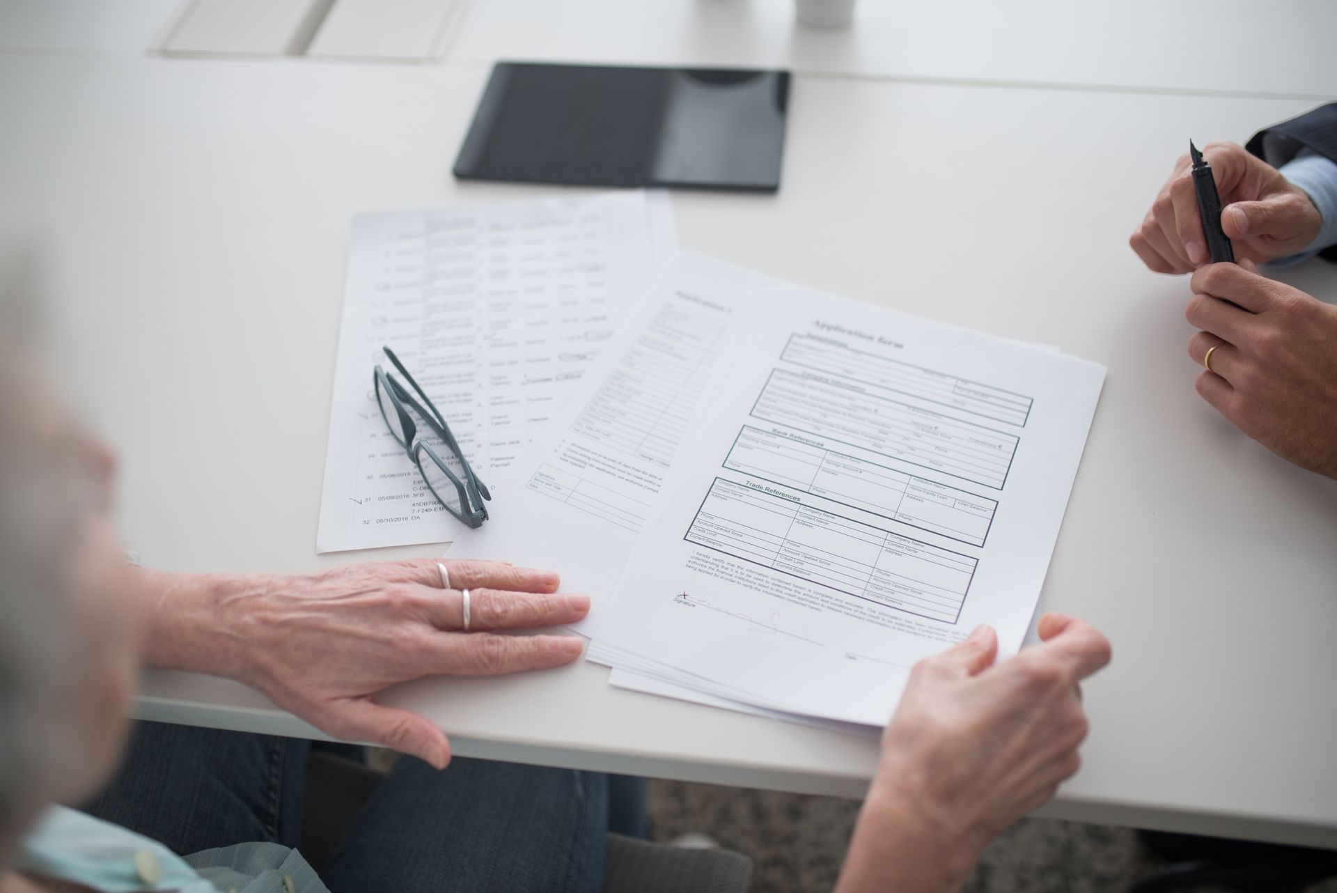 Two people reviewing official application documents and forms at a table